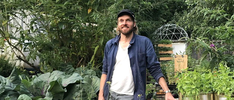Marco Clausen steht in einem urbanen Garten